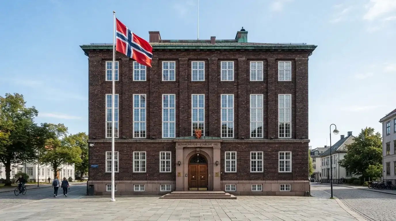 Offentlig kontorbygning i rødt murstein i en norsk by, med et flagg ved inngangen og blå himmel